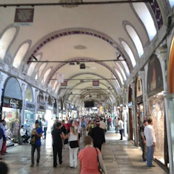 Människor som går och handlar på en livlig inomhusmarknad med välvda tak och många skyltfönster.