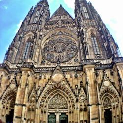 En stor, utsmyckad gotisk katedral med två höga torn, ett stort rosenfönster och invecklade sniderier. Människor samlas vid ingången.