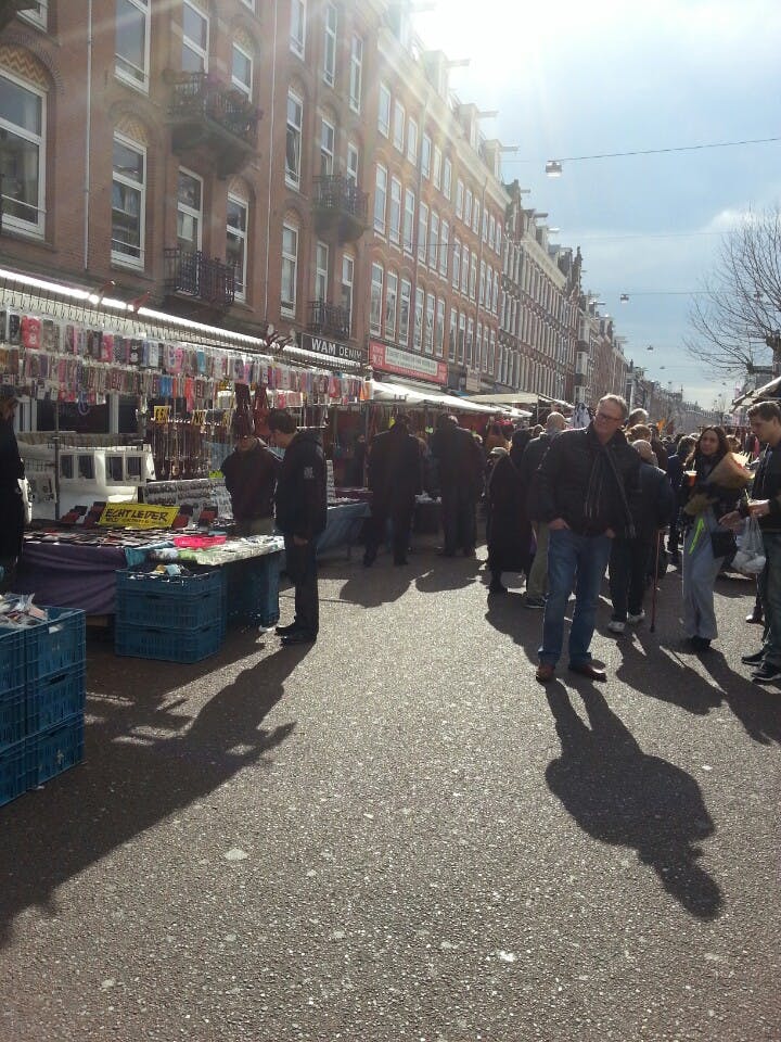 화창한 날 사람들로 붐비는 스카프와 옷 등 다양한 물건을 파는 상인들이 있는 길거리 시장.