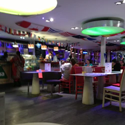 Ett pulserande café med internationella flaggor hängande, människor som sitter vid borden och en upplyst disk där personalen serverar mat.