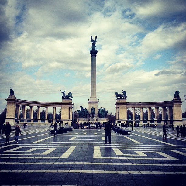 동상이 꼭대기에 있는 높은 기둥이 있는 커다란 광장에는 사람들이 걸어다니는 동상이 있는 두 개의 콜로네이드가 있습니다.