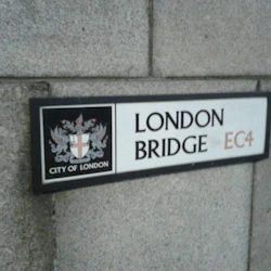 Skylt med texten "London Bridge EC4" med City of Londons vapensköld, monterad på en stenmur.